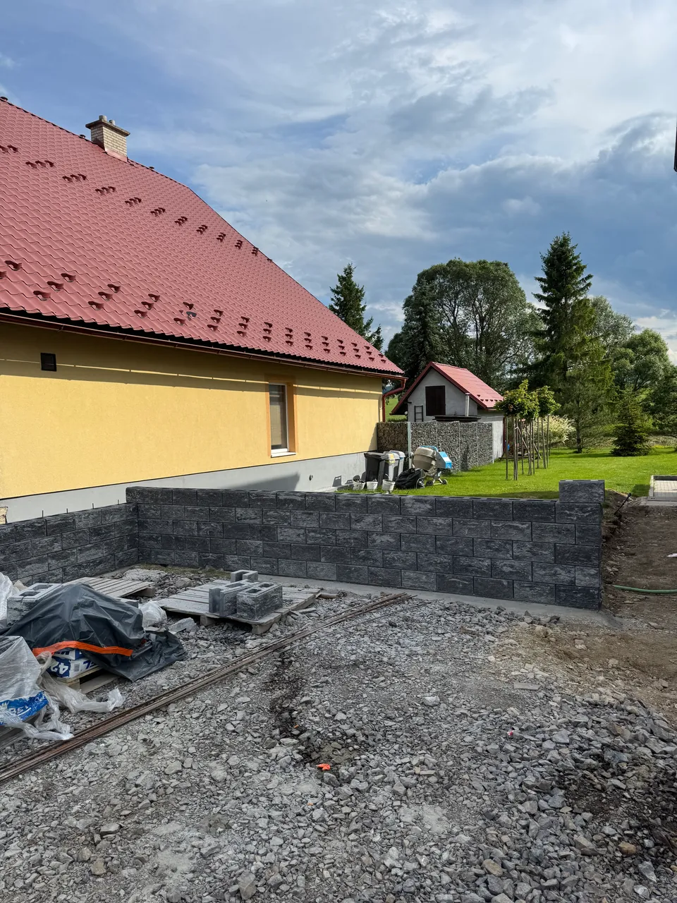 Murovaný plot zo sivých betónových tvárnic počas výstavby