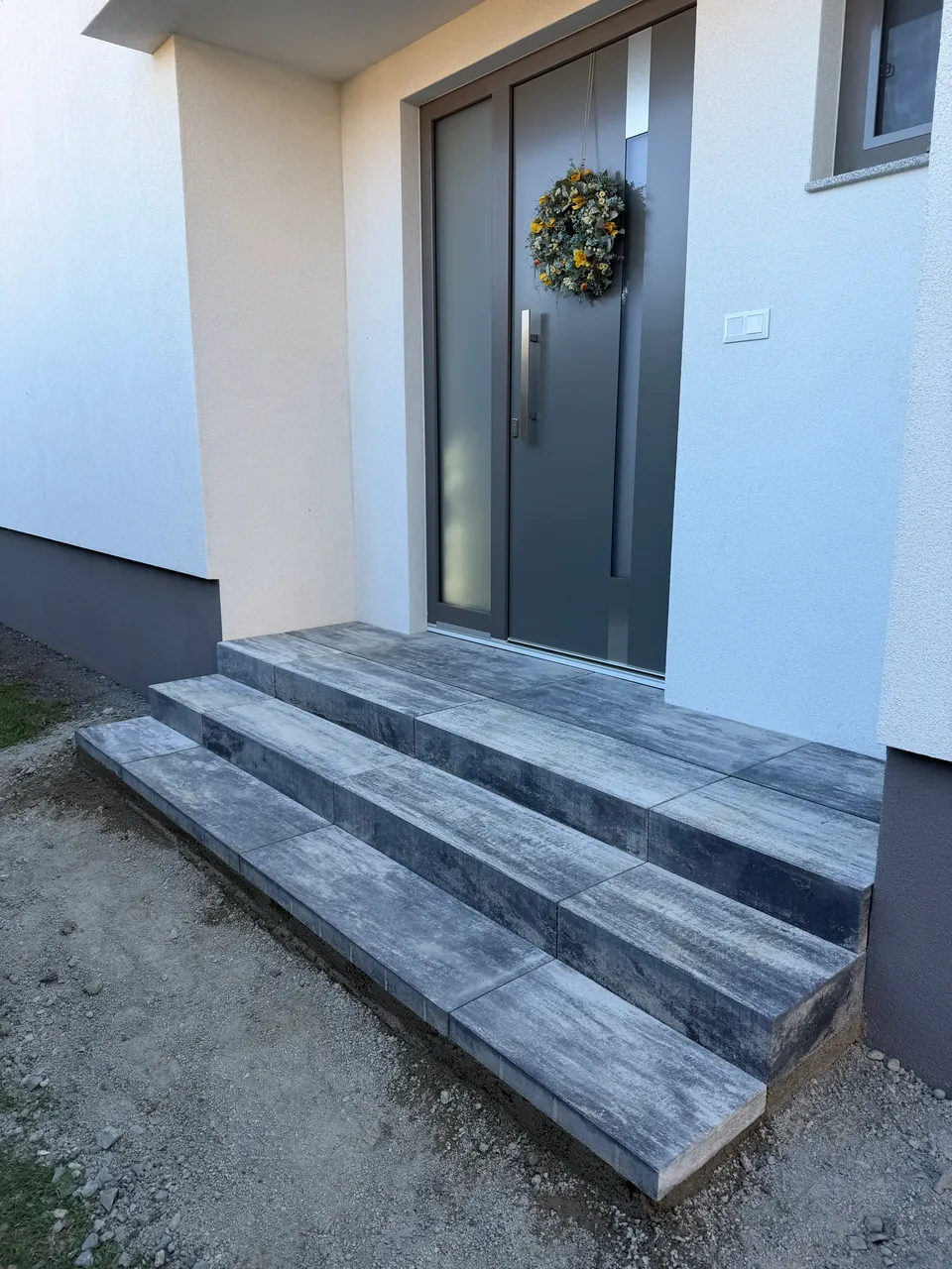 Vstupné schody obložené sivými veľkoformátovými platňami